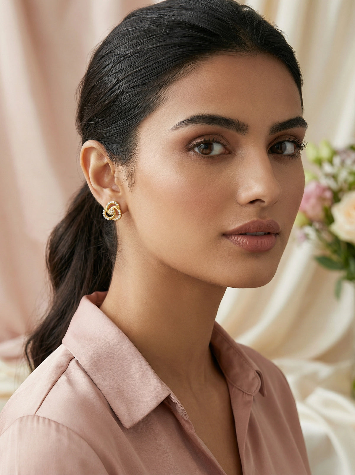 woman wearing 18k gold plated earrings with a soft focus background
