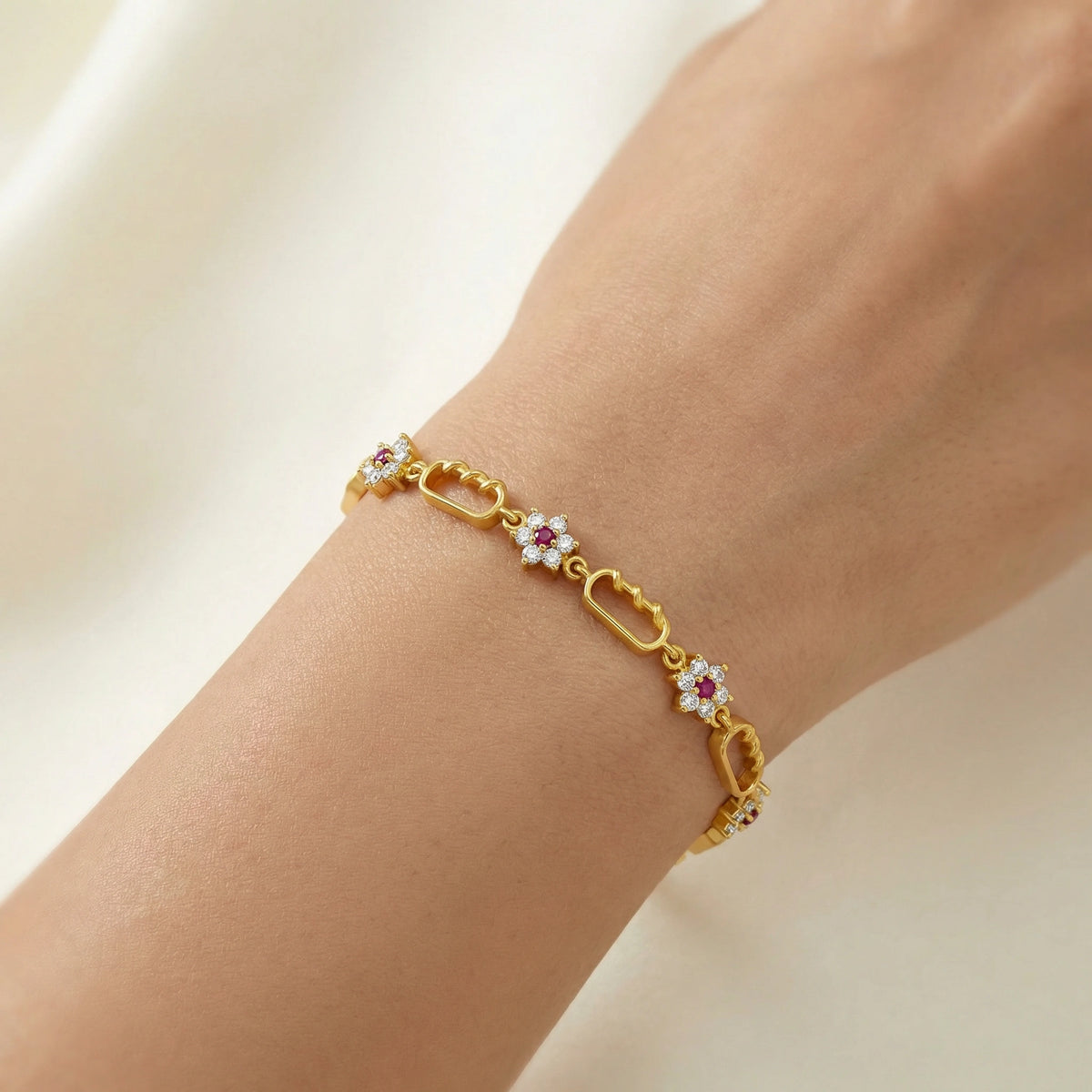 18k gold plated bracelet with floral links on a wrist against a neutral background