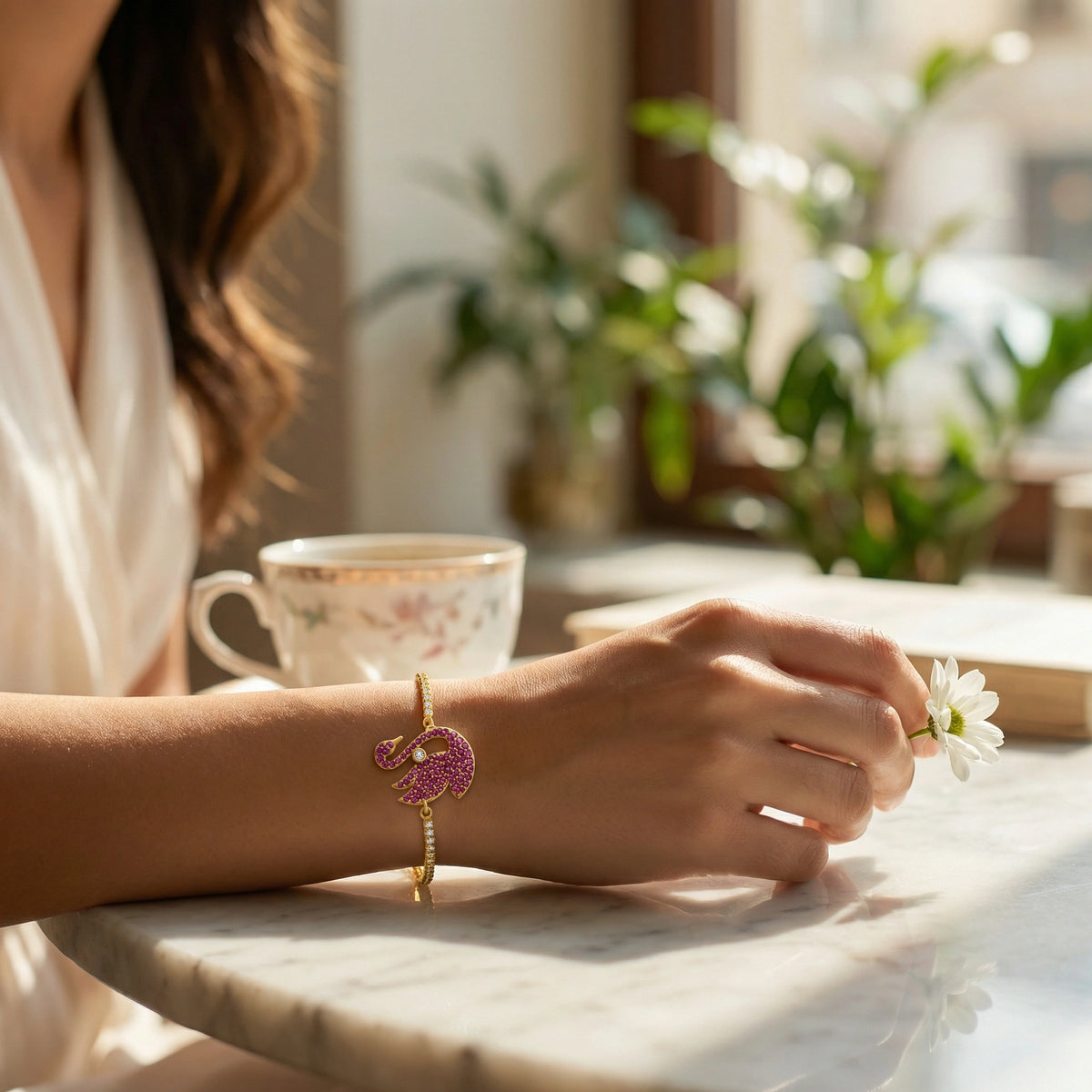 person holding a flower with 18k gold plated  bracelet on a table in a bright room with plants