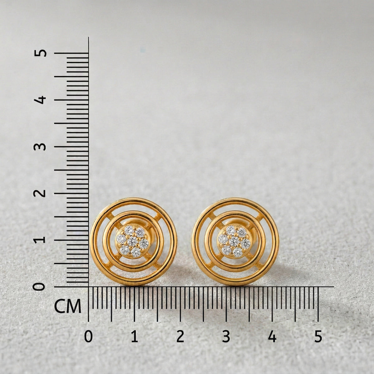 18k Gold plated earrings with diamond accents next to a ruler on a light gray background