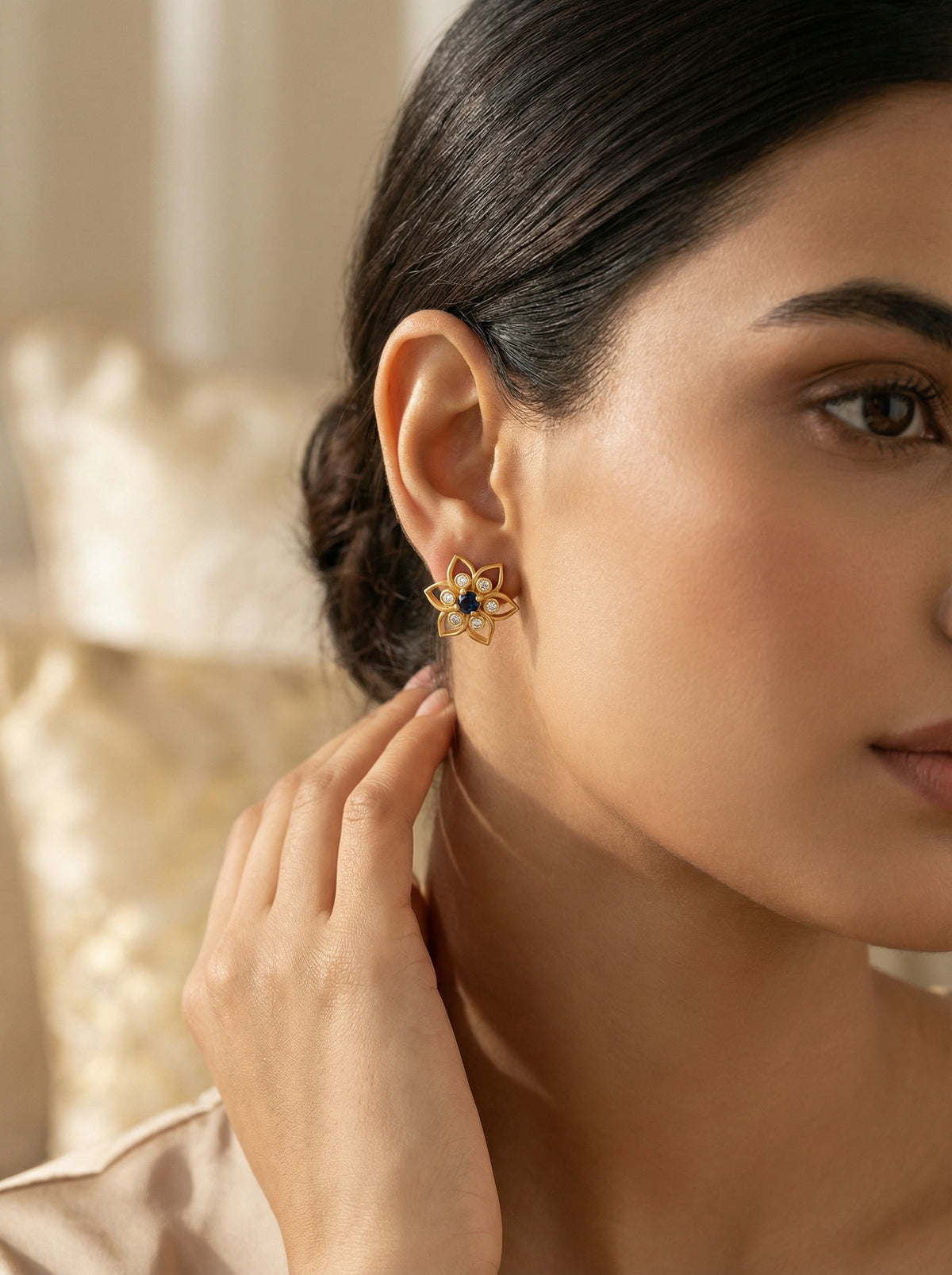 close-up of a woman wearing a 18k  gold plated earring with a dark gemstone.