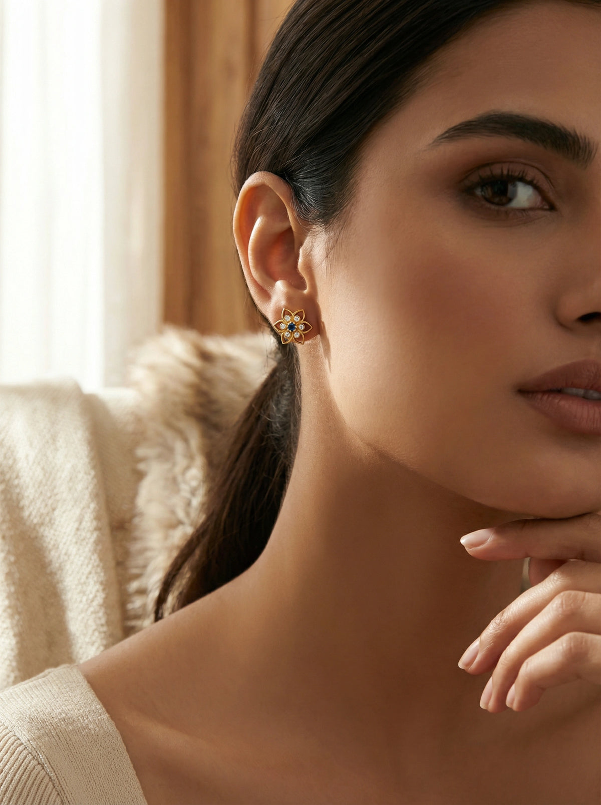 close-up of a woman wearing a 18k  gold plated  earring with a gemstone, indoors.