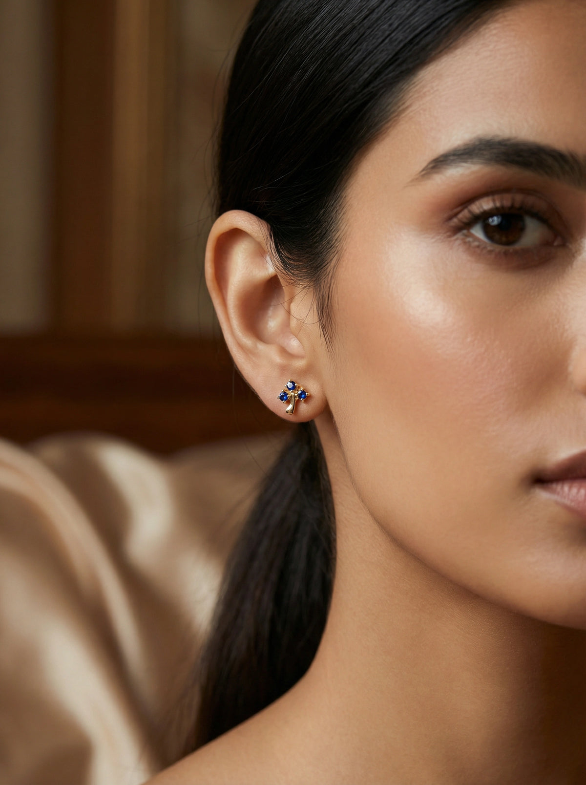 close-up of a woman wearing a pair of 18k gold plated earrings with a blurred background