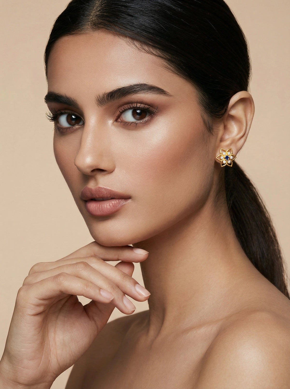 woman wearing a floral 18k gold plated  earring against a beige background