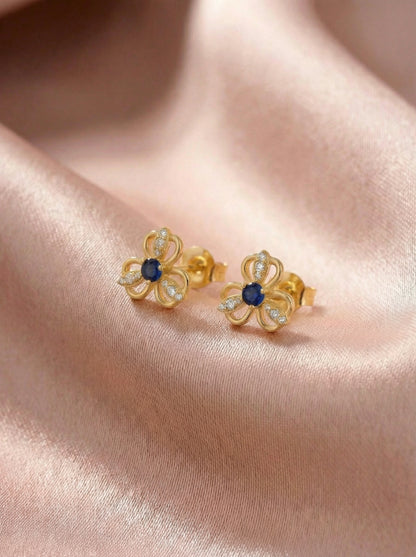 18k Gold plated flower-shaped earrings with blue centers on a pink fabric background