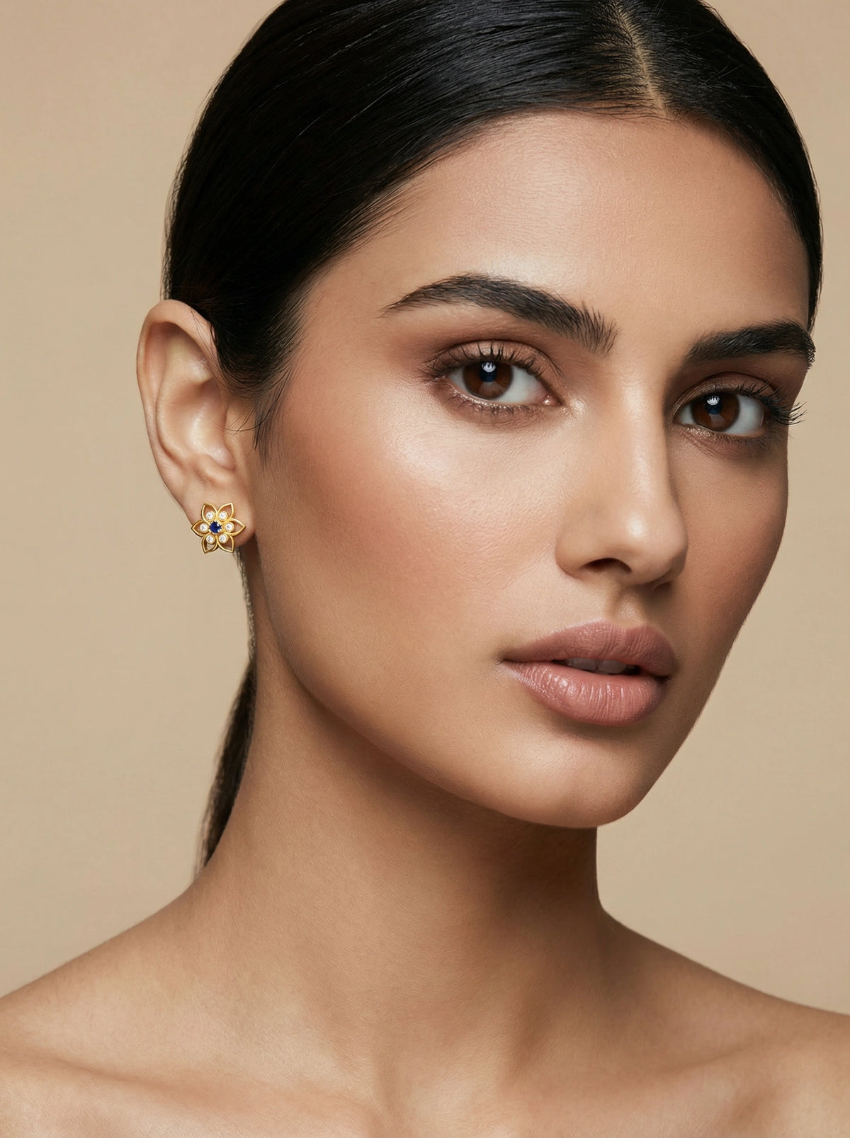 close-up of a woman wearing 18k gold plated wearrings with a beige background