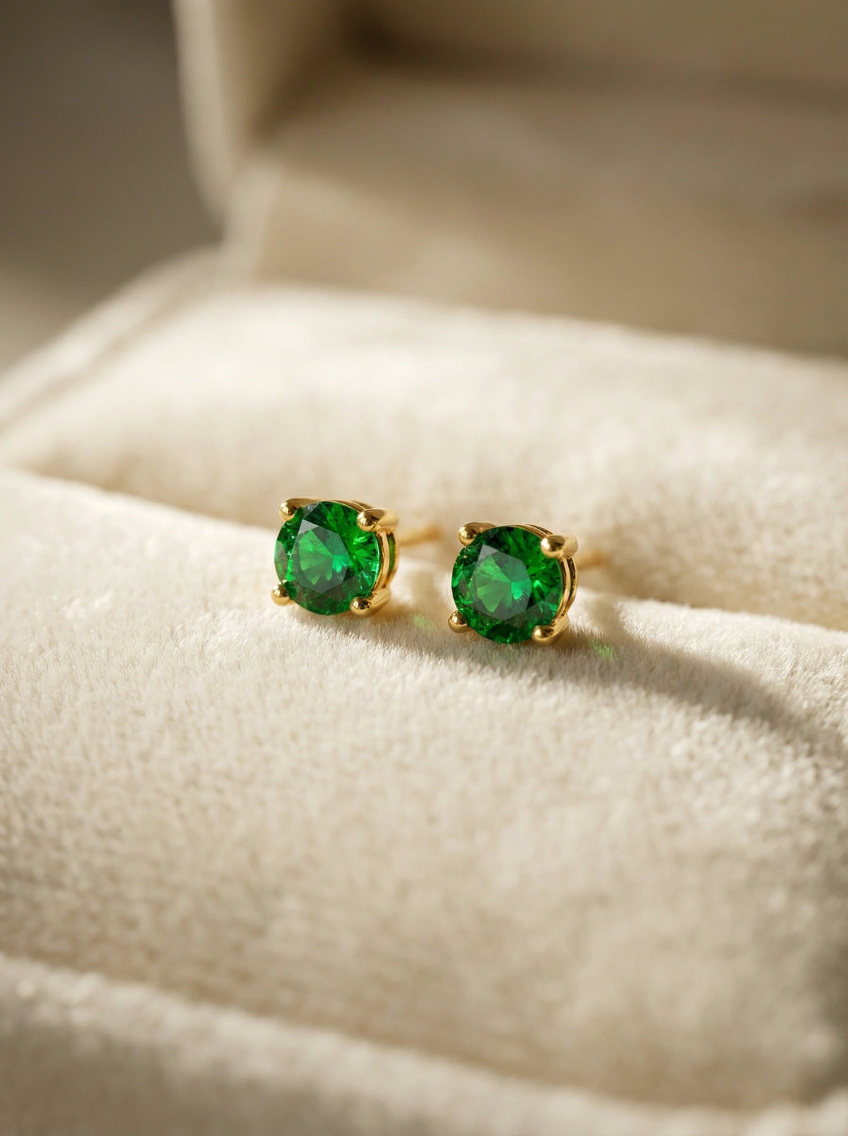 green gemstone 18k golde plated  earrings on a soft fabric surface