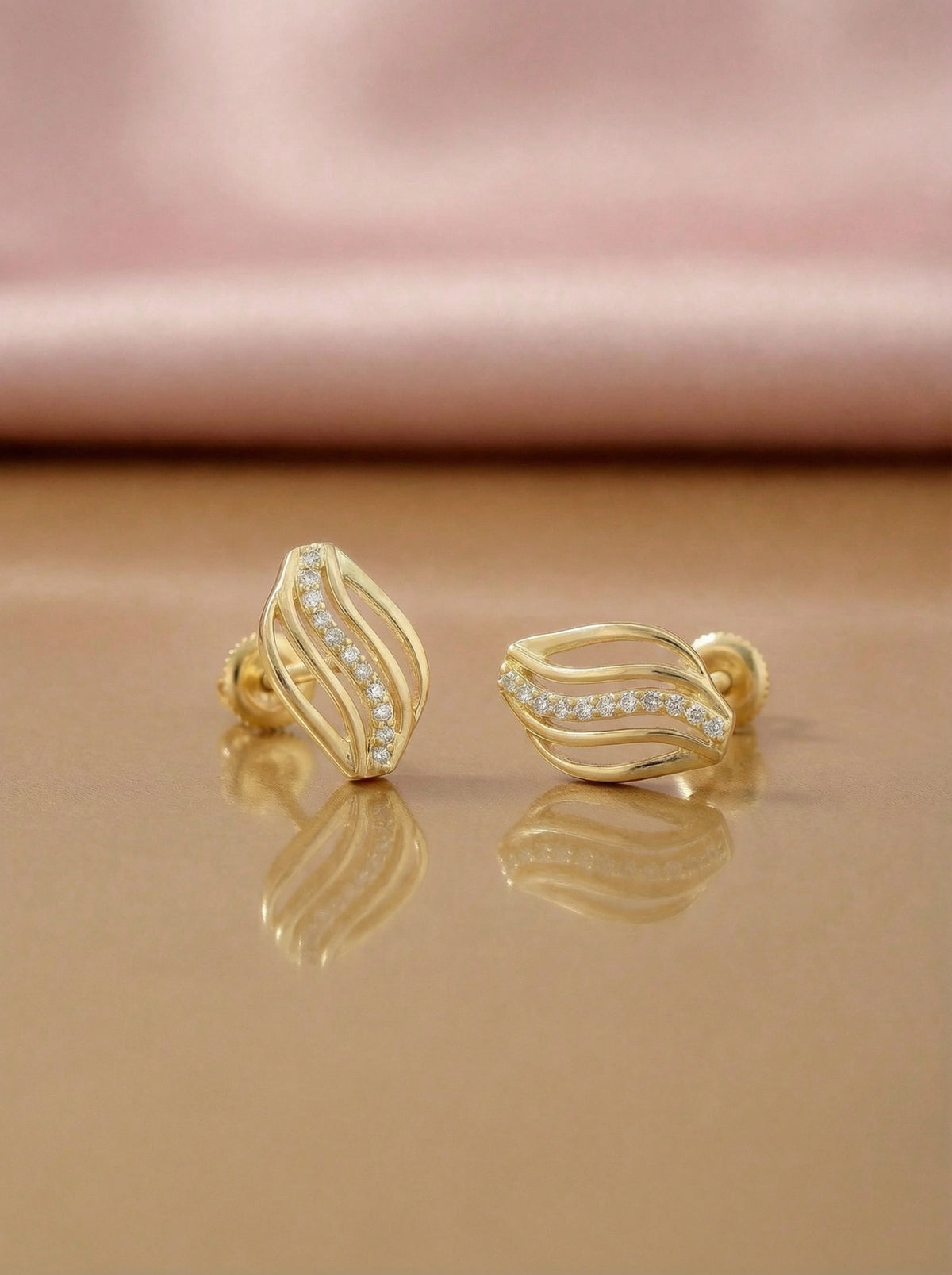 18k Gold plated earrings with diamond accents on a reflective surface