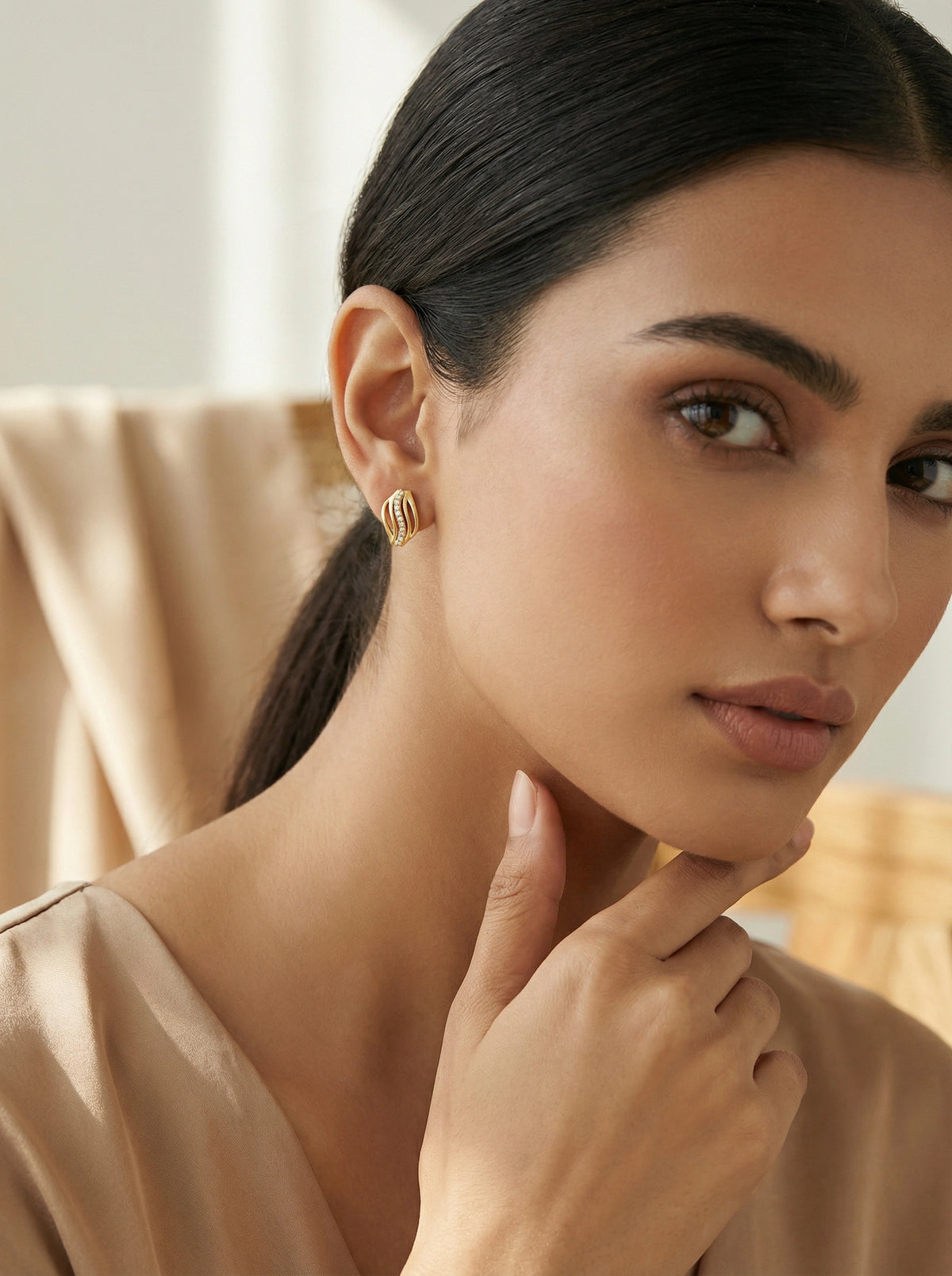 woman wearing 18k  gold plated earrings with a neutral background