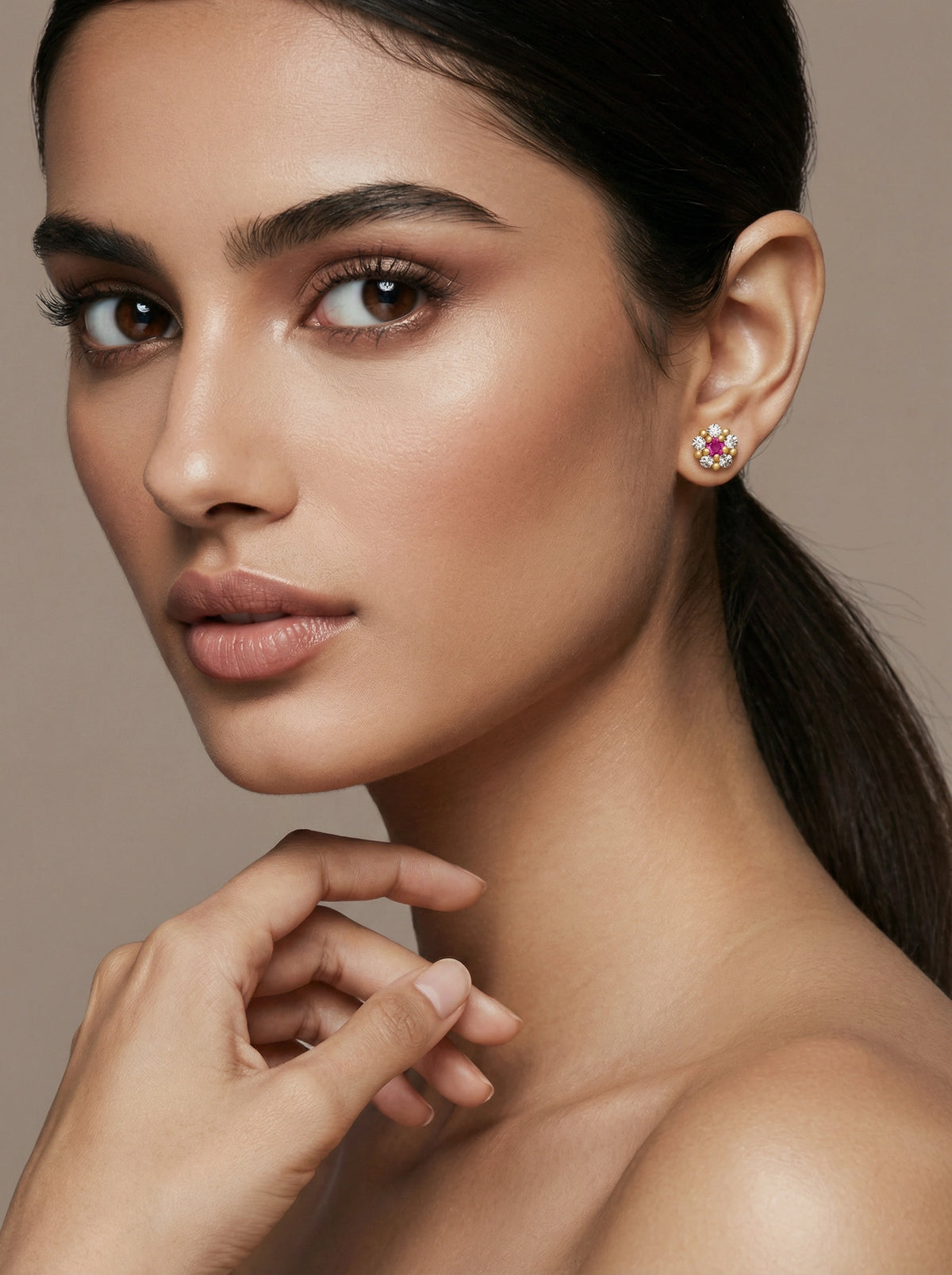 close-up of a woman wearing a pink gemstone 18k gold plated  earring against a neutral background