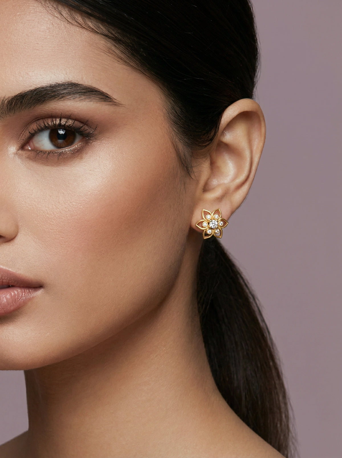 close-up of a woman wearing a 18k  gold plated earring with a purple background