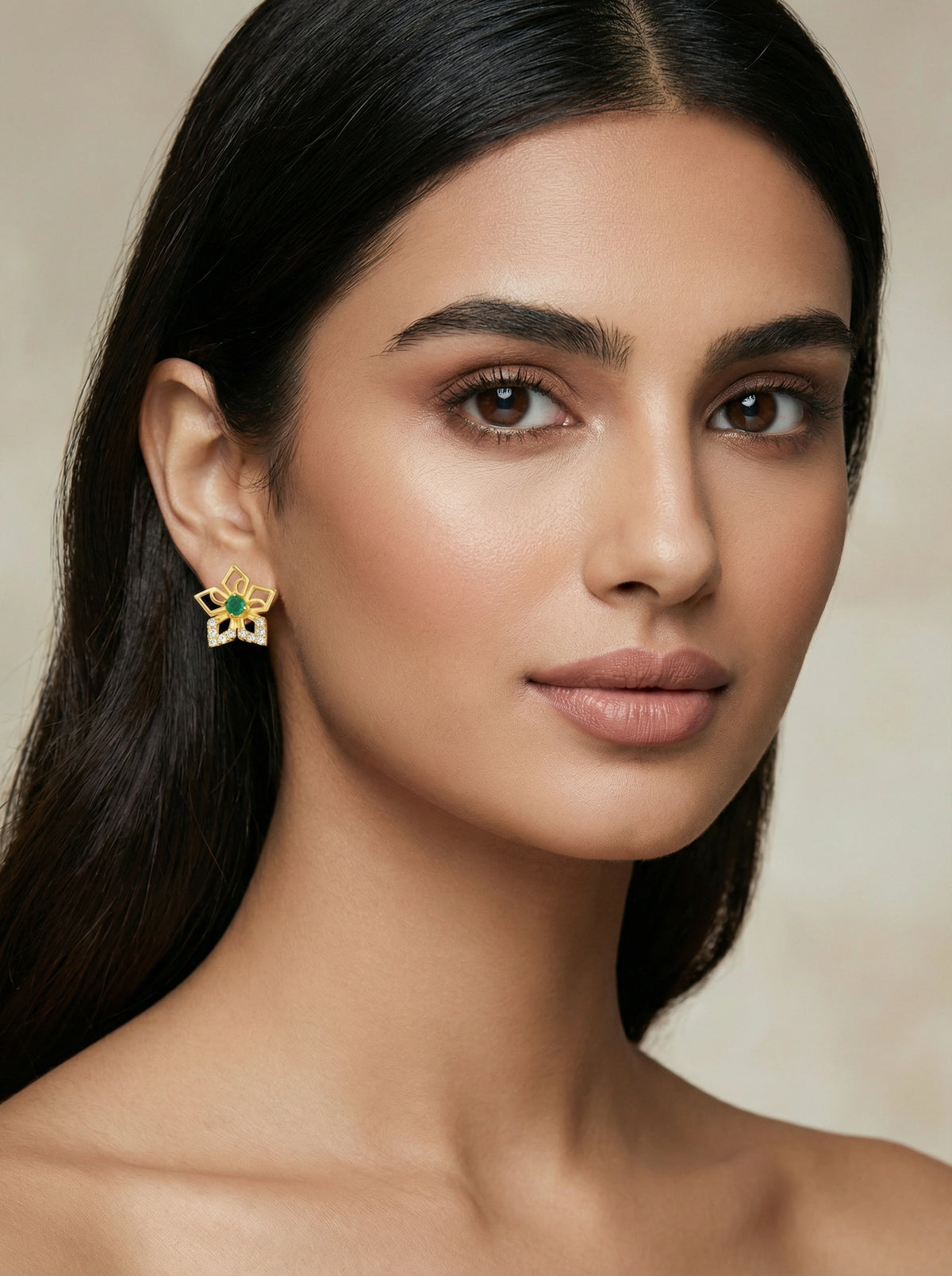 close-up of a woman wearing a floral 18k gold plated earring with a neutral background