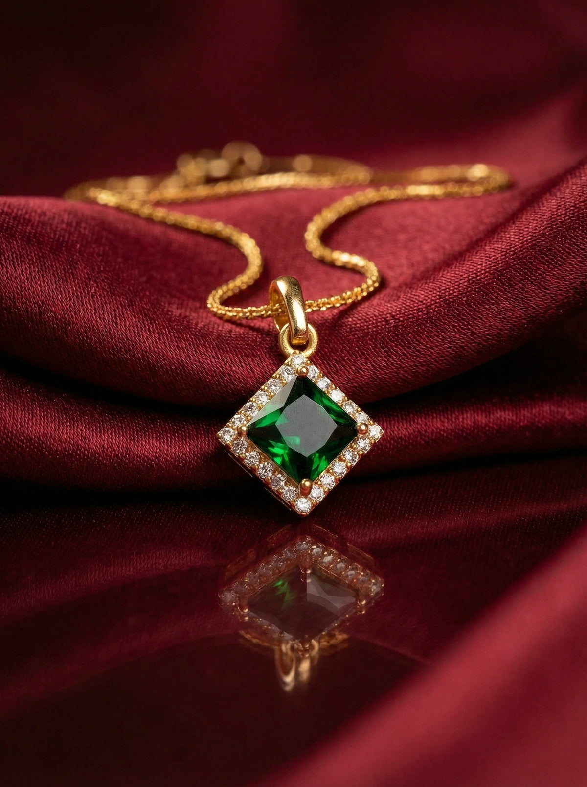 18k gold plated necklace with a green gemstone pendant on a red fabric background