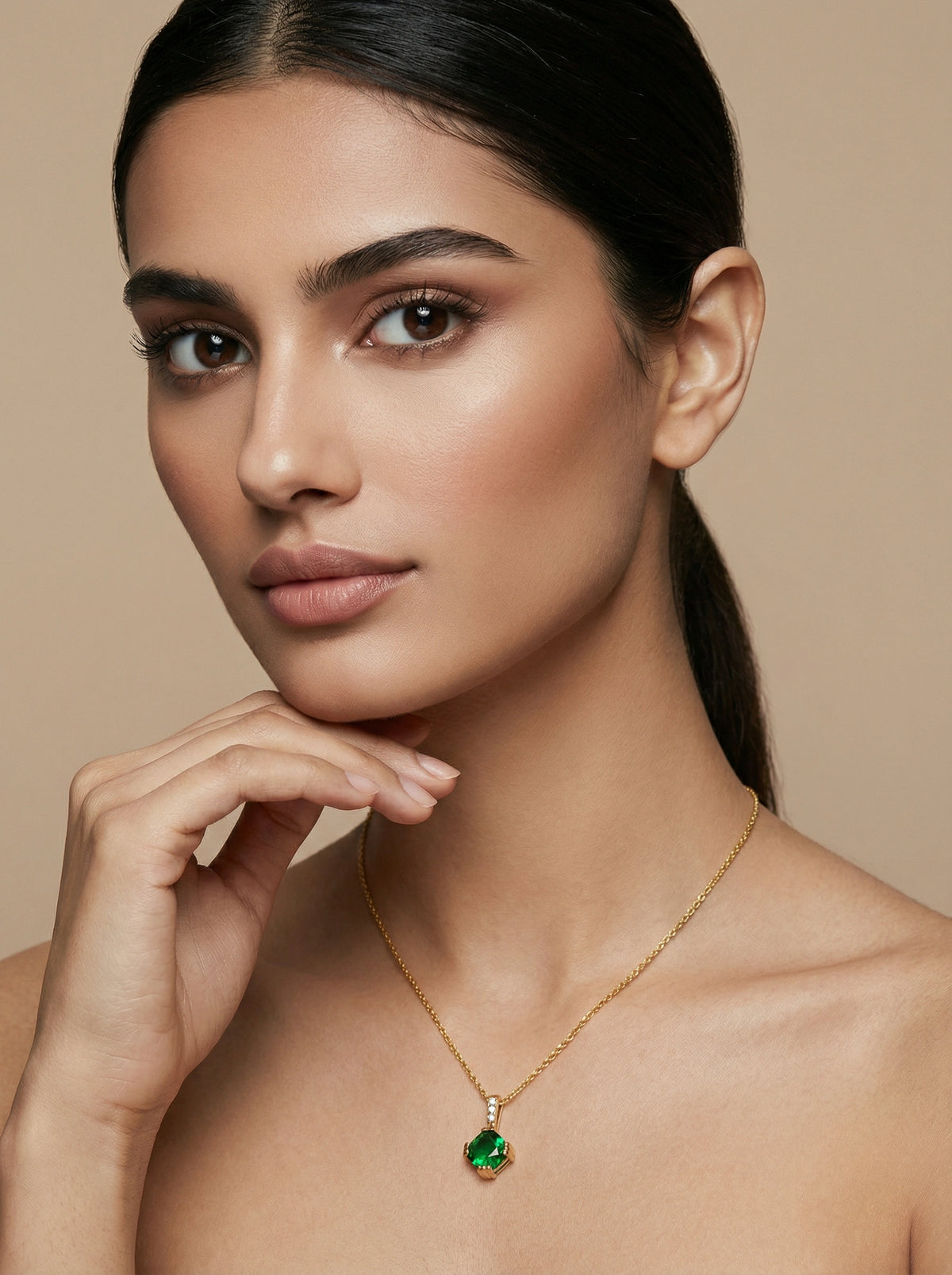 woman wearing a 18k gold plated necklace with a green pendant against a beige background
