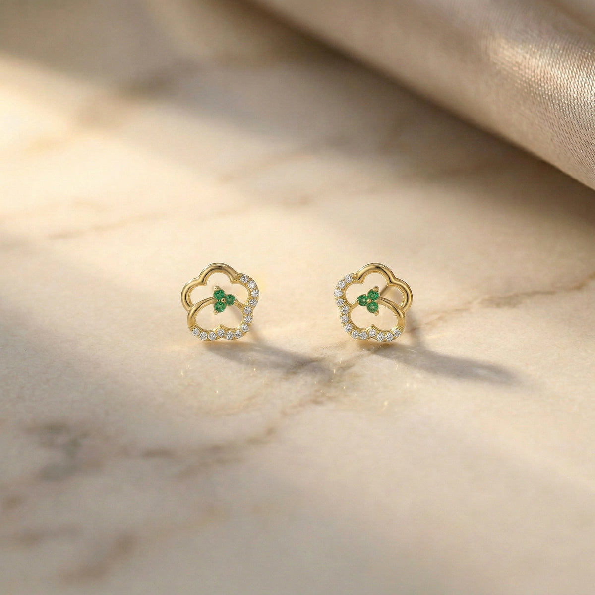 18k gold plated earrings with green gemstones on a marble surface