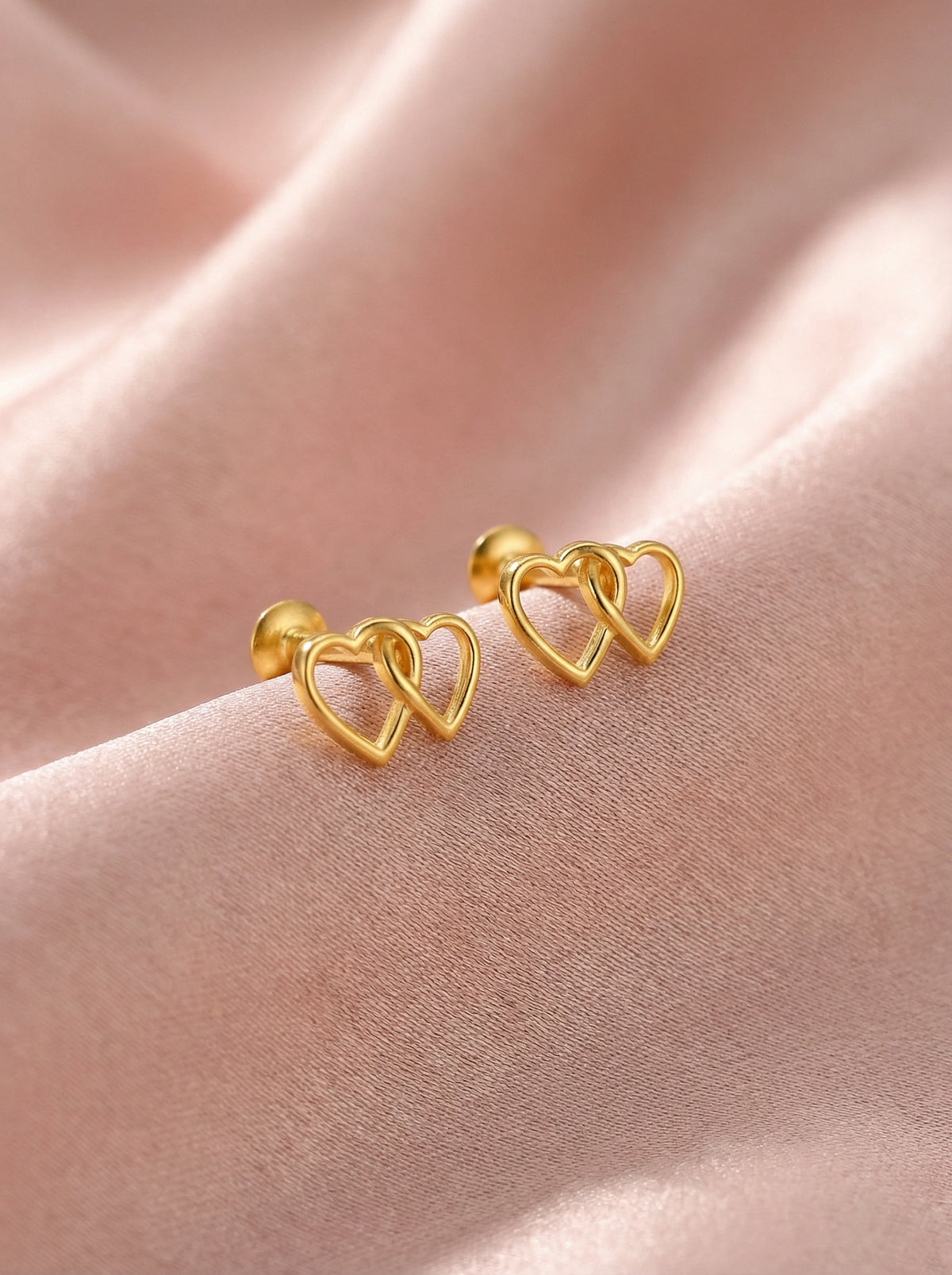 18k Gold plated heart-shaped earrings on a pink fabric background