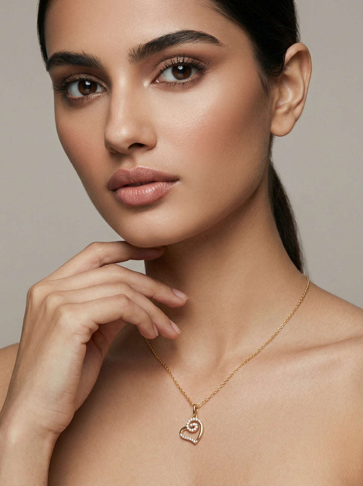 woman wearing a 18k gold plated necklace with a heart pendant against a neutral background