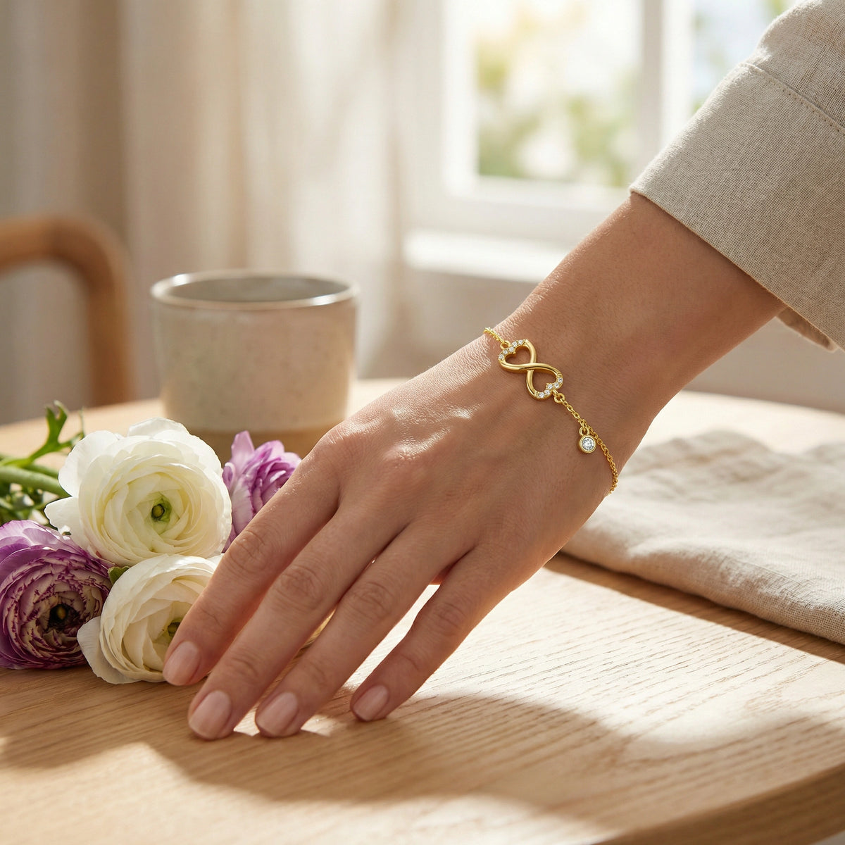 hand wearing 18k  gold plated  bracelet with flowers and a mug in the background