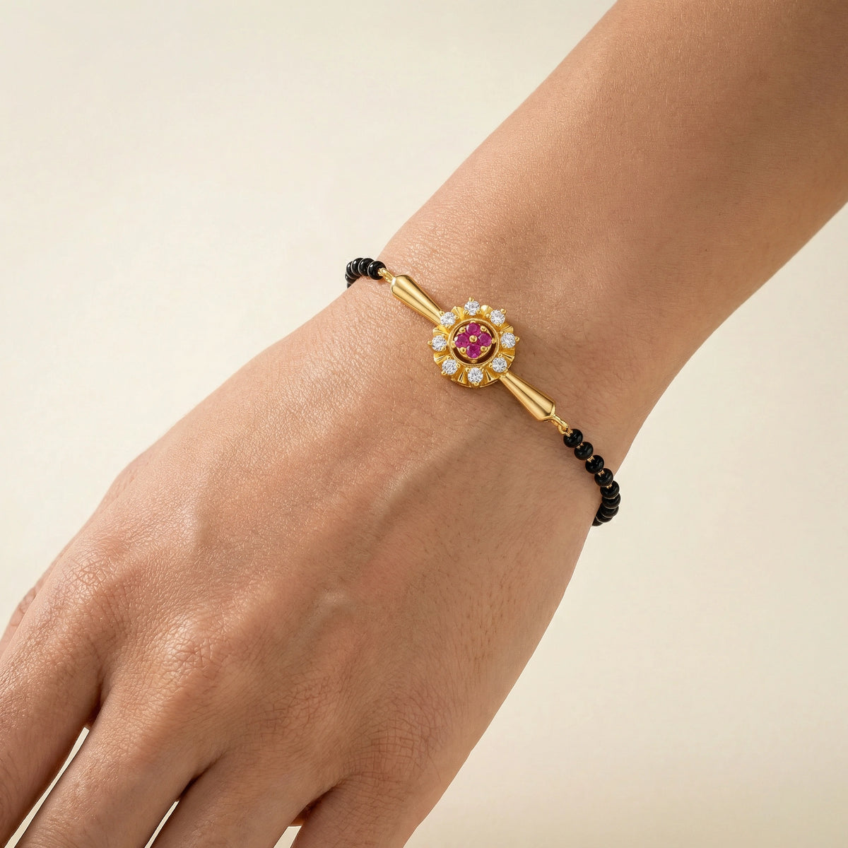 18k gold plated bracelet with a pink gemstone on a wrist against a beige background