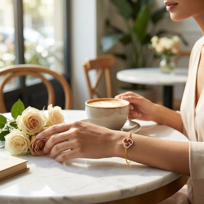 wear 18k gold plated bracelet Person holding a cup of coffee with flowers on a table in a cafe.