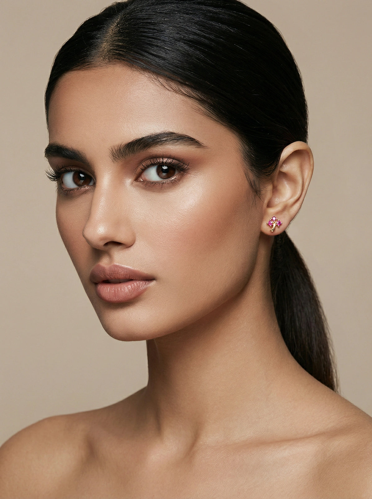 woman wearing pink 18k gold plated earrings against a beige background