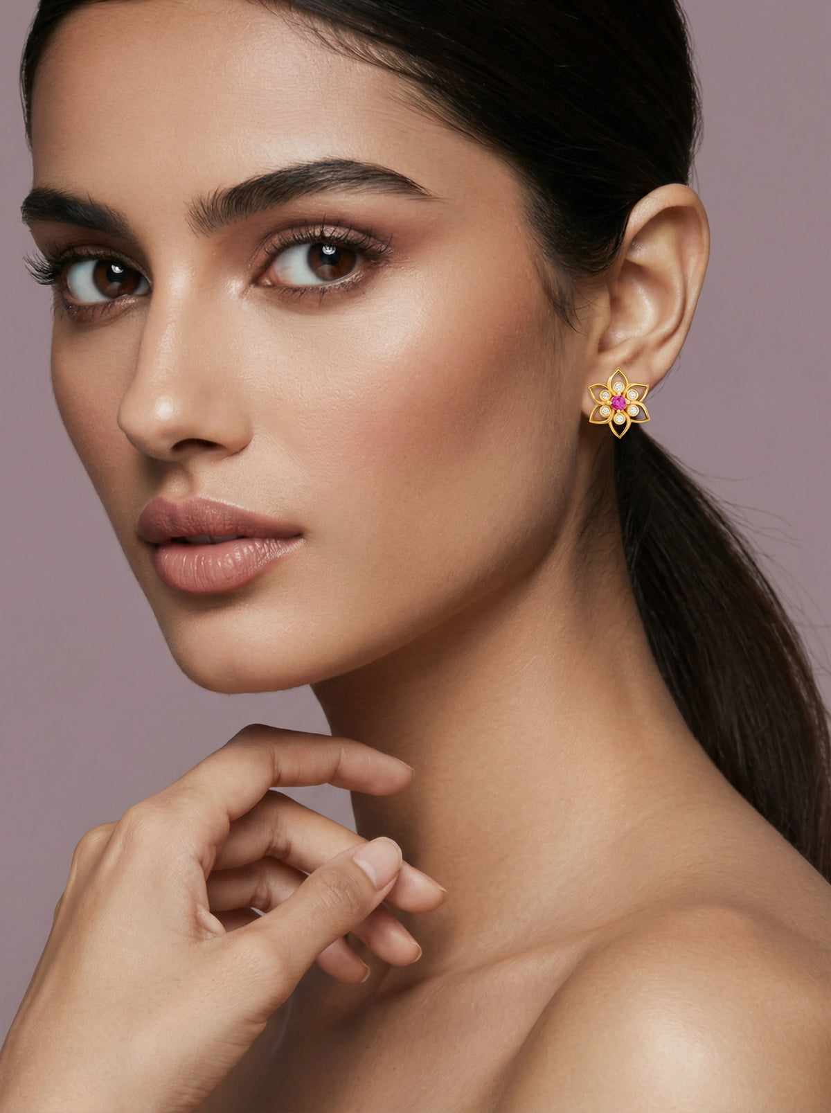 close-up of a woman wearing a floral 18k gold plated earring against a neutral background