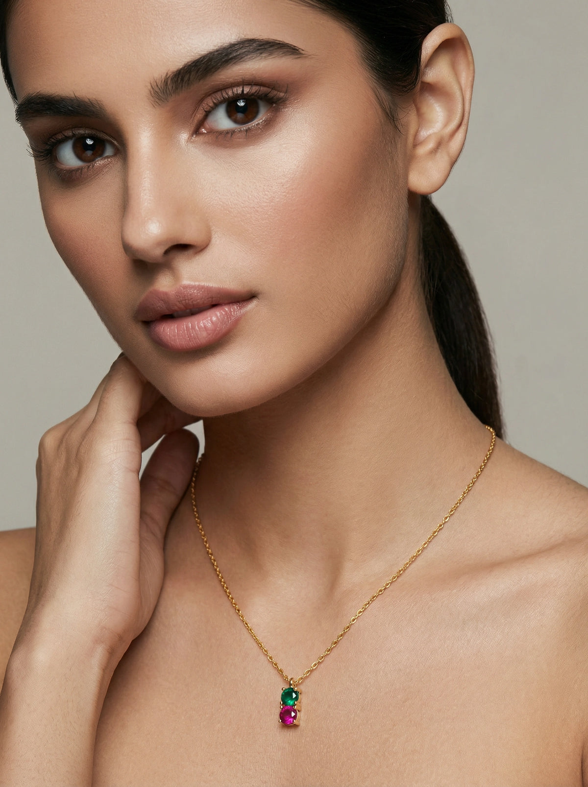 woman wearing a 18k gold plated necklace with gemstones against a neutral background