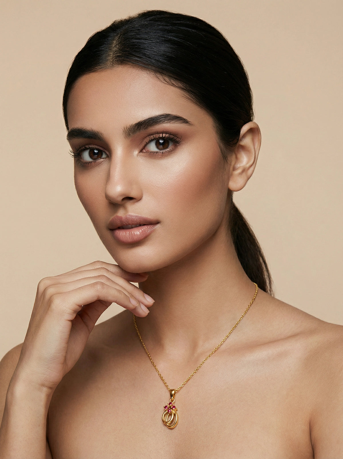 woman wearing a 18k  gold plated necklace with a pink pendant against a beige background