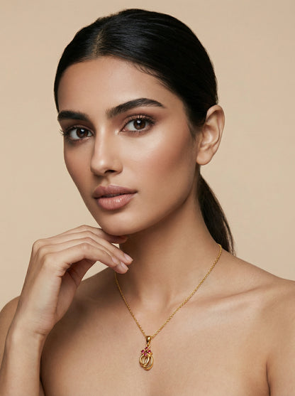 Woman wearing a 18k  gold plated necklace with a pink pendant against a beige background
