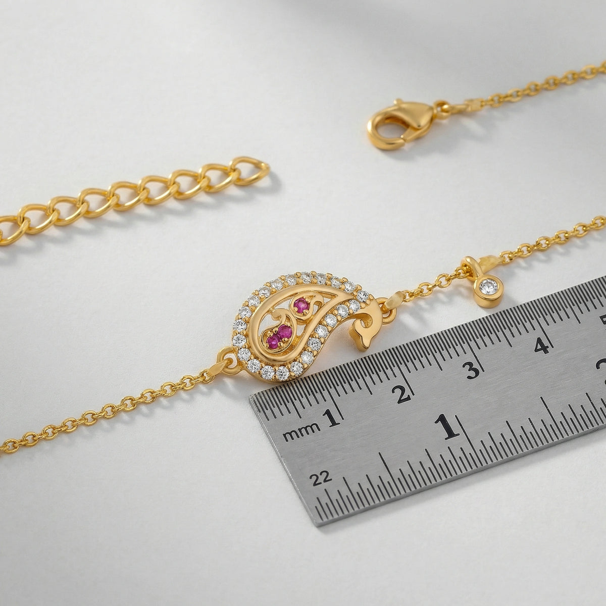 18k Gold plated bracelet with a decorative clasp and gemstones next to a ruler on a light gray background