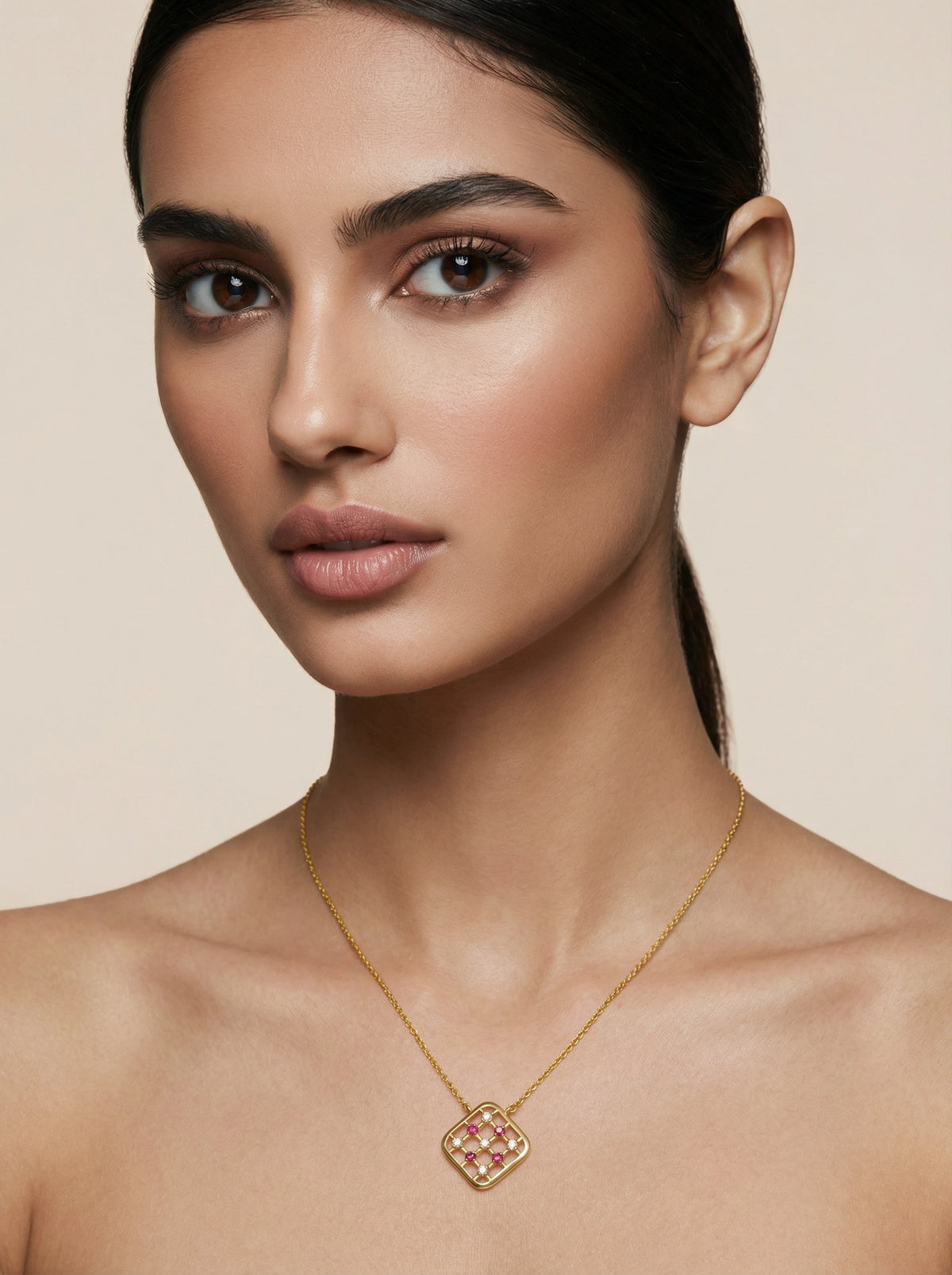 woman wearing a 18k  gold plated necklace with a detailed pendant against a beige background