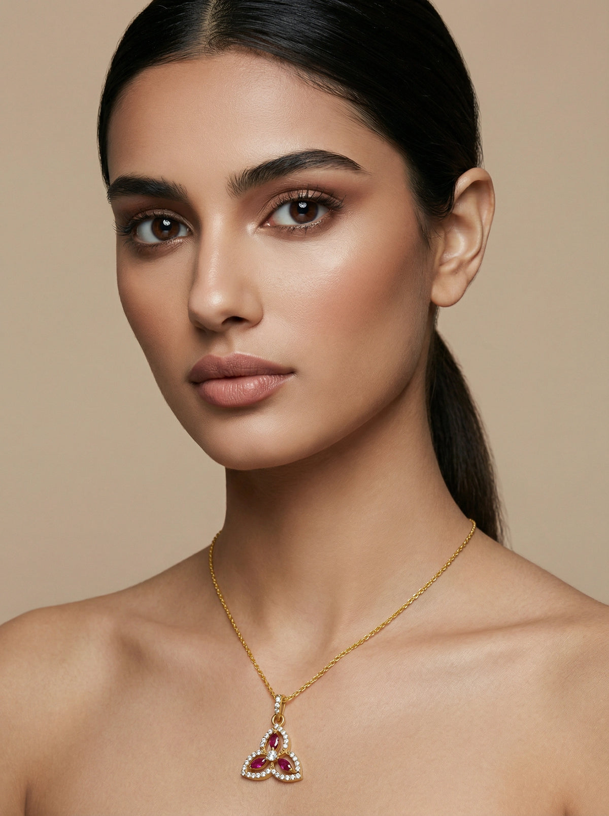 woman wearing a 18k  gold plated necklace with a red gemstone pendant on a beige background
