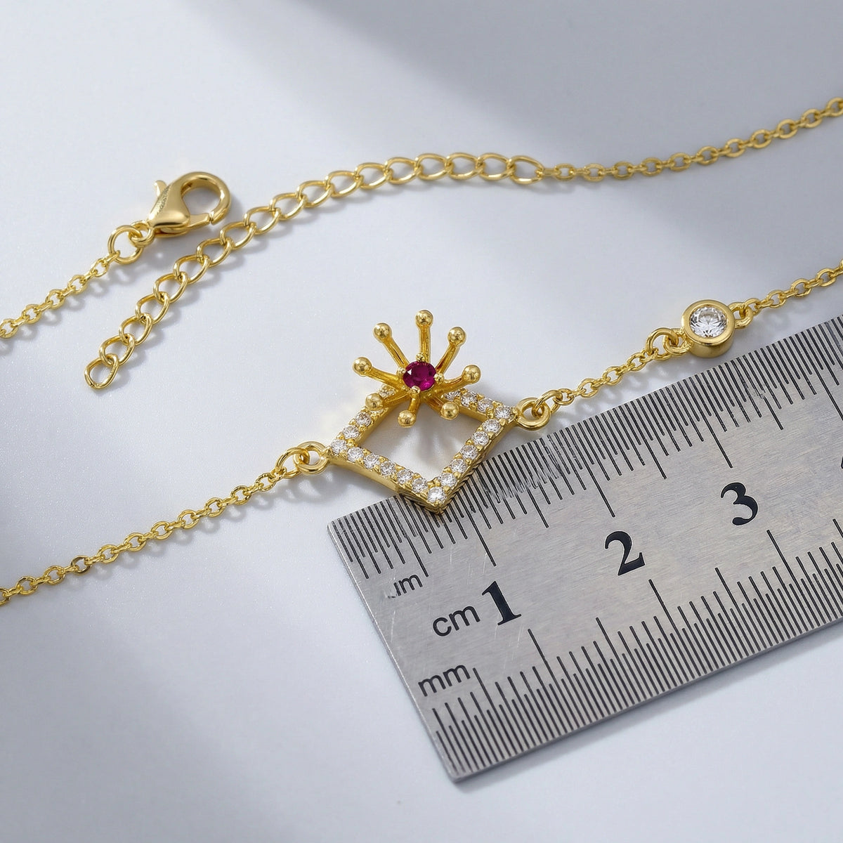 18k Gold plated bracelet with a decorative clasp next to a ruler on a light gray background