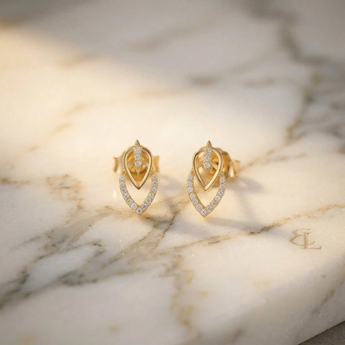 18k gold plated earrings with diamond accents on a marble surface