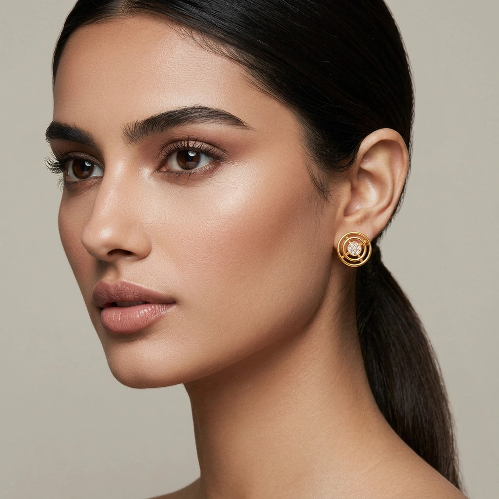 close-up of a woman wearing 18k gold plated earrings against a neutral background