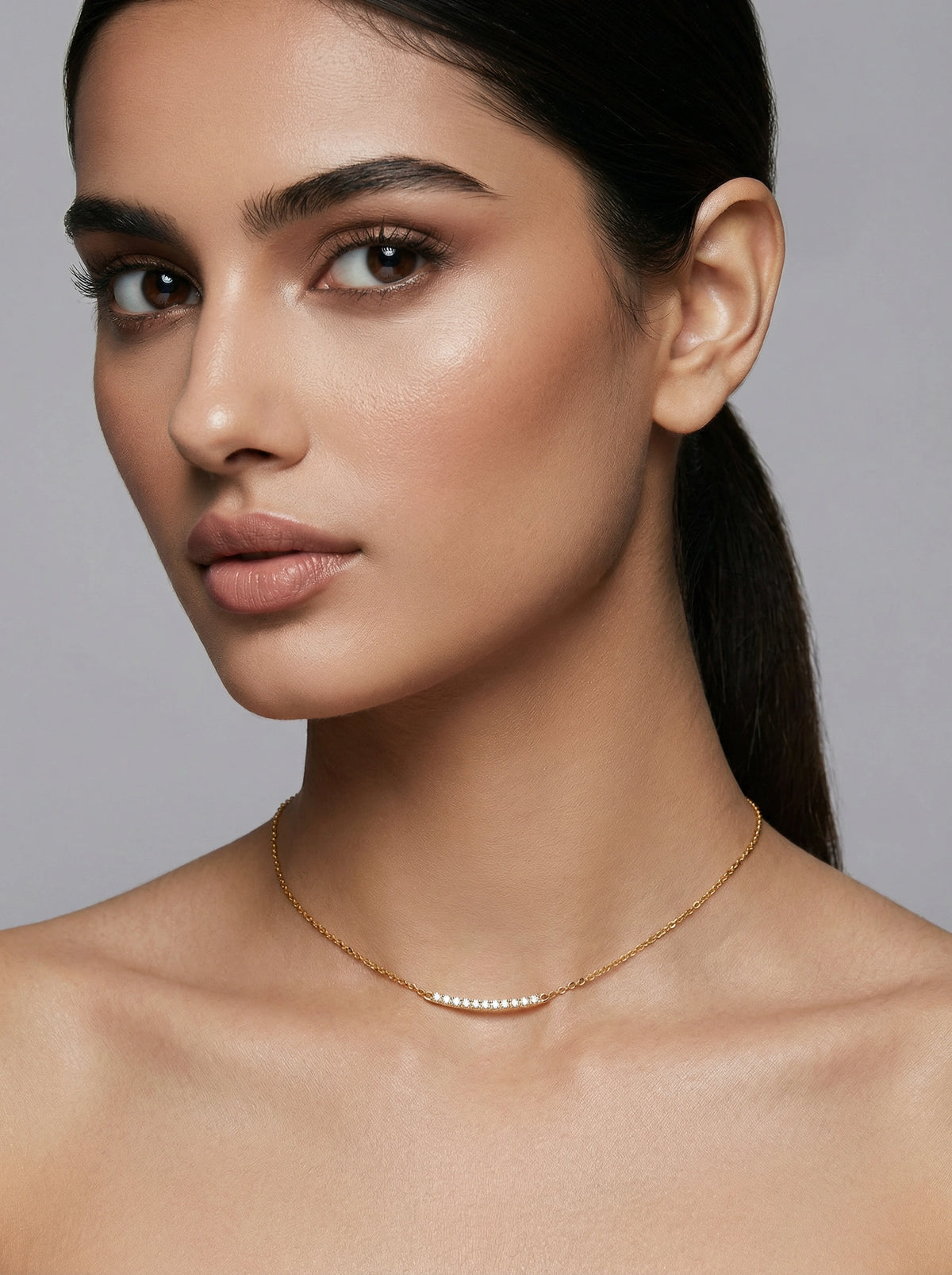 woman wearing a delicate 18k gold plated necklace against a neutral background