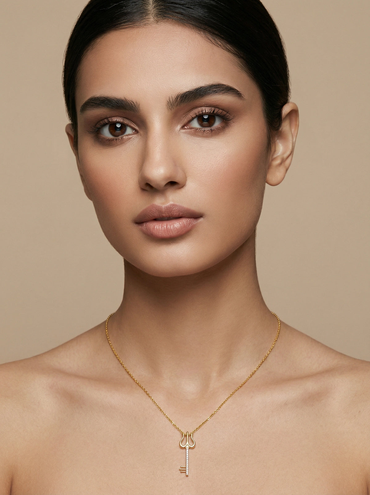 woman wearing a  18k gold plated necklace with a key pendant against a beige background