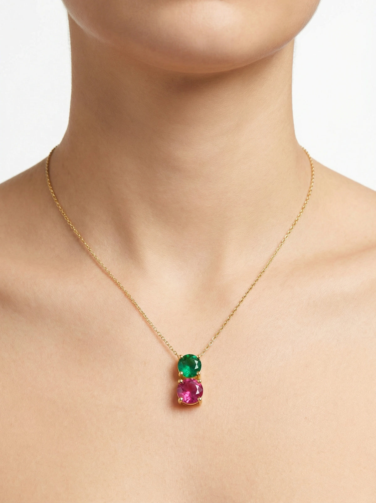 18k gold plated necklace with green and pink gemstones on a plain background