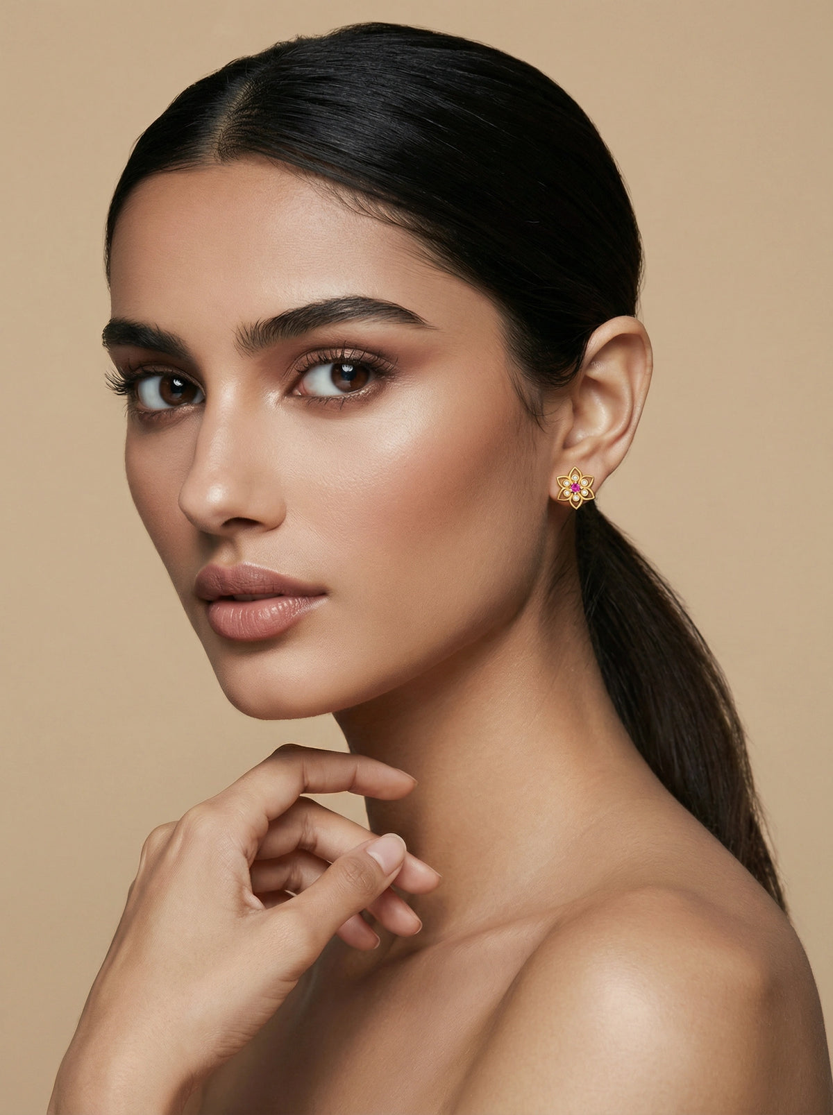 woman with a smooth neck and ear, wearing a 18k  gold plated  earring against a beige background