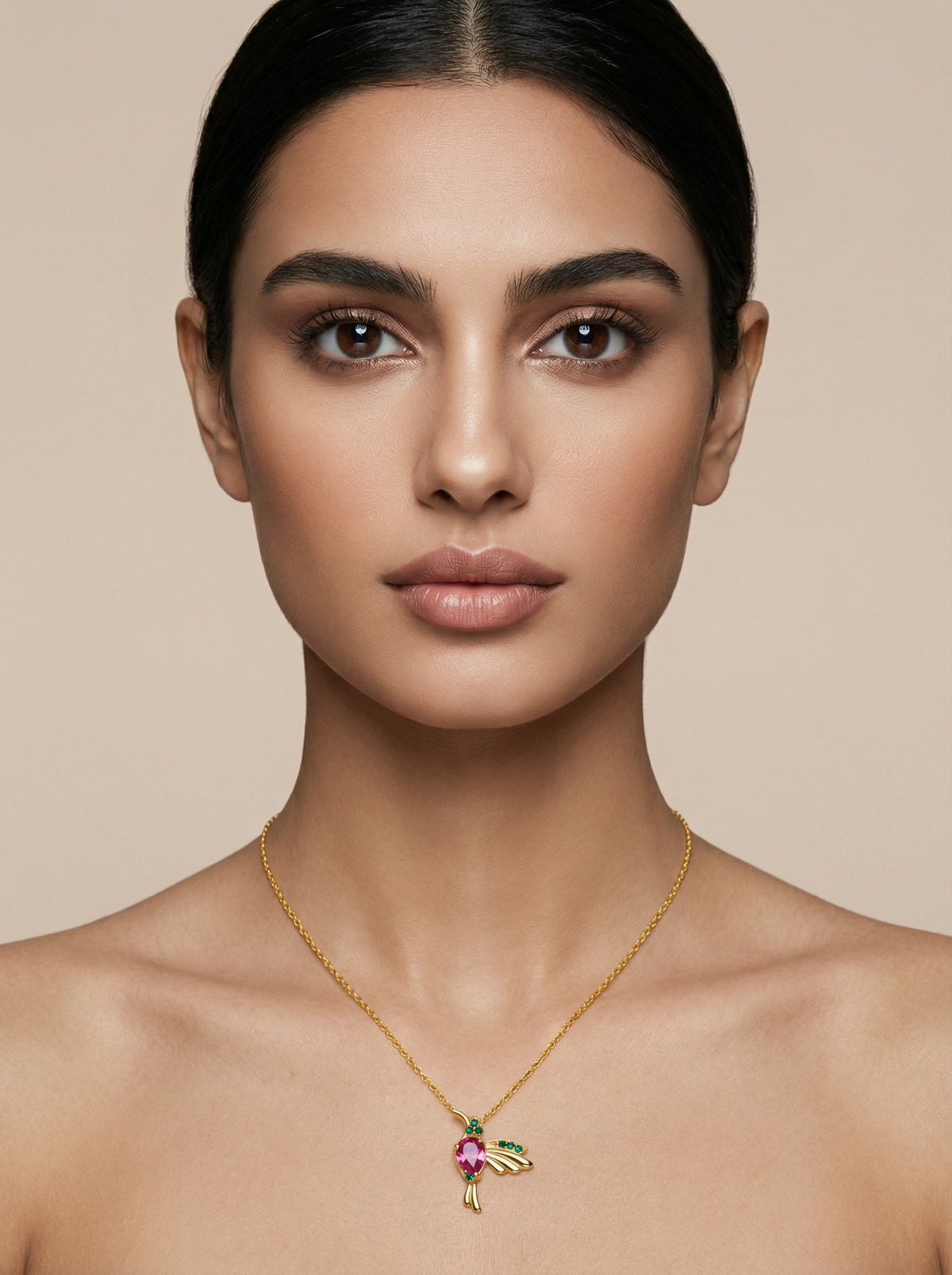 Woman wearing a 18k gold plated necklace with a colorful pendant against a beige background