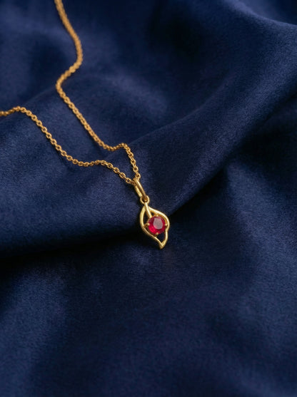 18k Gold plated necklace with a red gemstone pendant on a dark blue fabric background