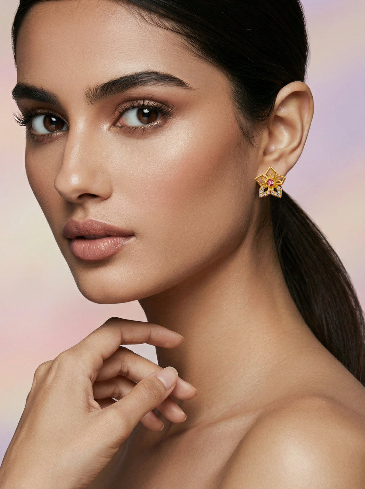 close-up of a woman wearing a 18k gold plated earring with a colorful gemstone against a soft gradient background.
