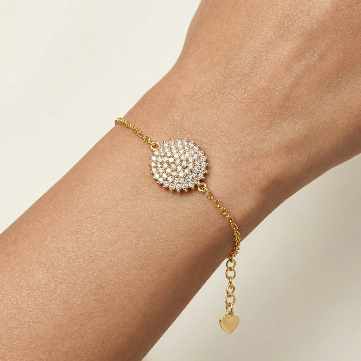 18k gold plated bracelet with a heart charm on a wrist against a beige background