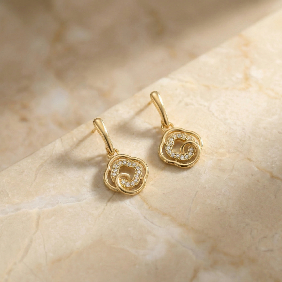 18k gold plated earrings on a beige marble surface