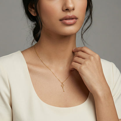 Woman wearing a 18k gold plated necklace with a key pendant against a neutral background