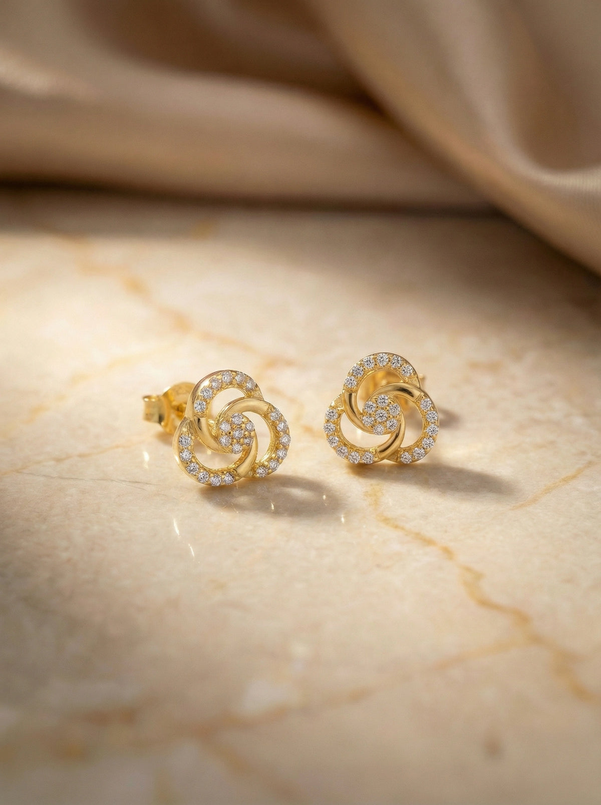 18k gold plated earrings with diamond accents on a marble surface
