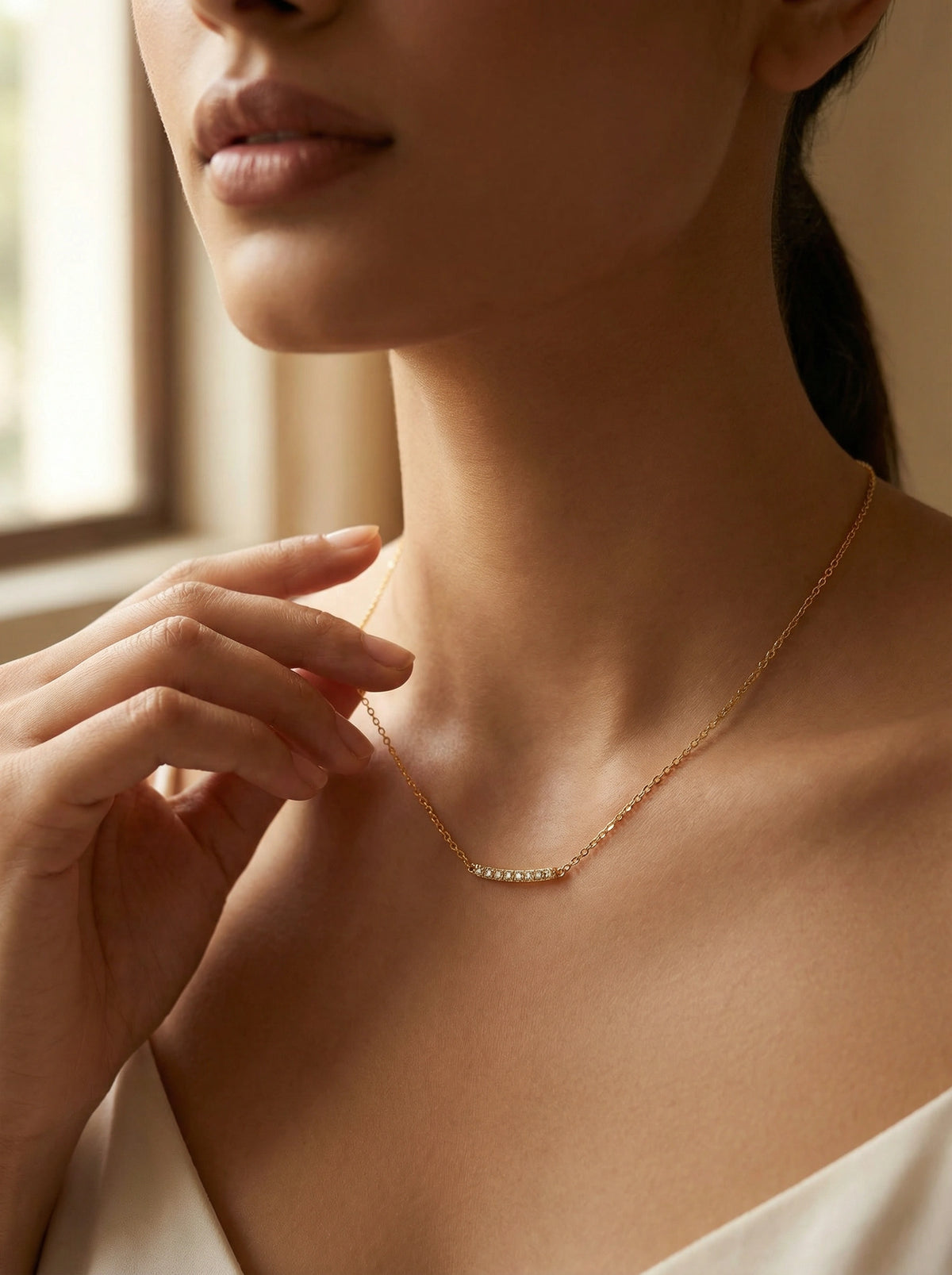 close-up of a woman wearing a delicate 18k gold plated necklace with a blurred background