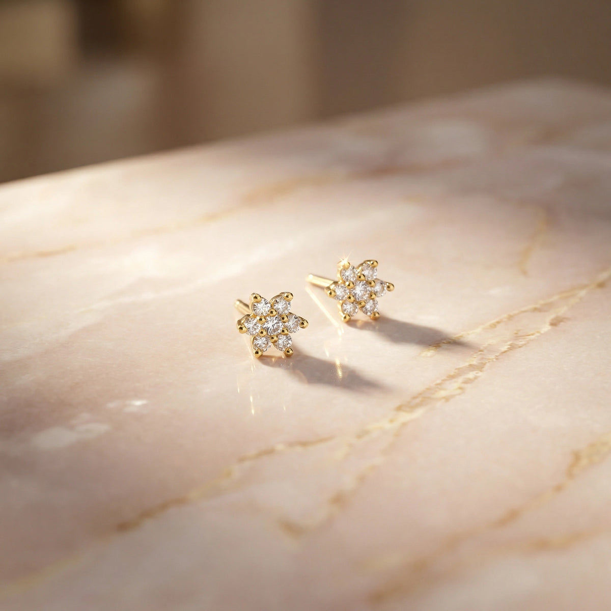 18k gold plated floral earrings on a marble surface