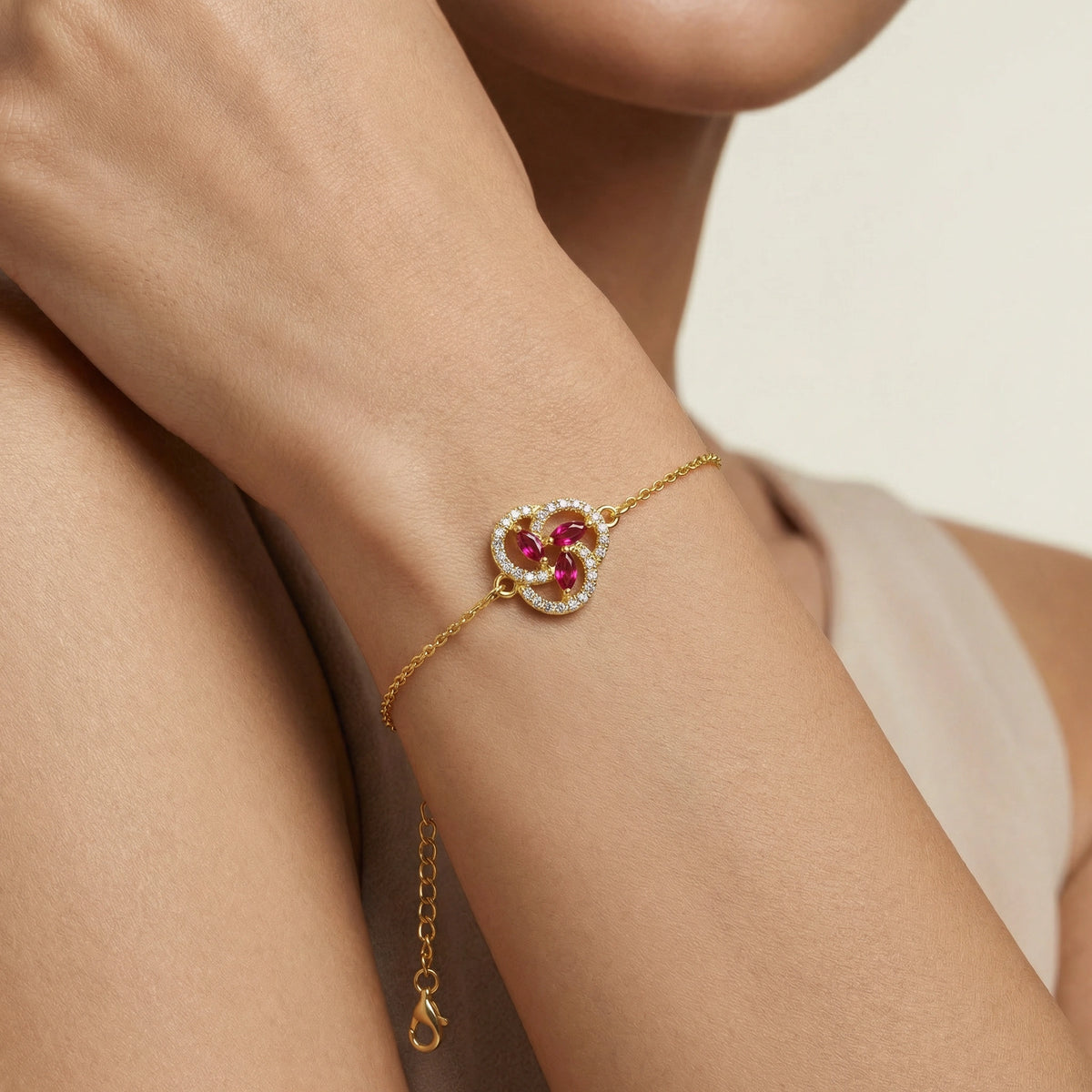 18k gold plated bracelet with red gemstones on a wrist against a neutral background