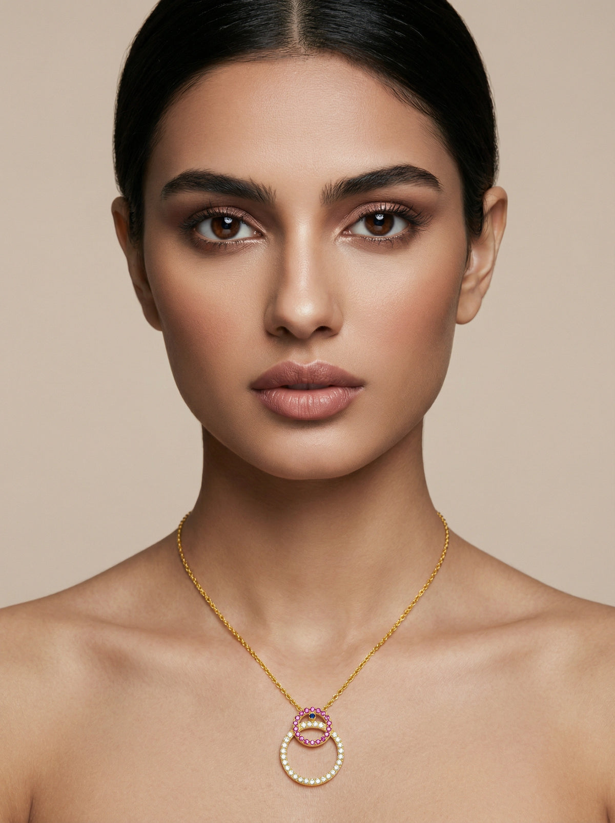 woman wearing a 18k  gold plated necklace with a pink pendant against a beige background